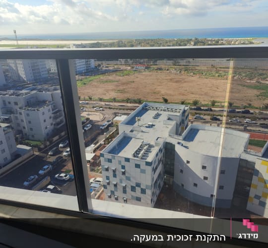 נוף עירוני מבעד לחלון זכוכית עם מסגרת מתכת